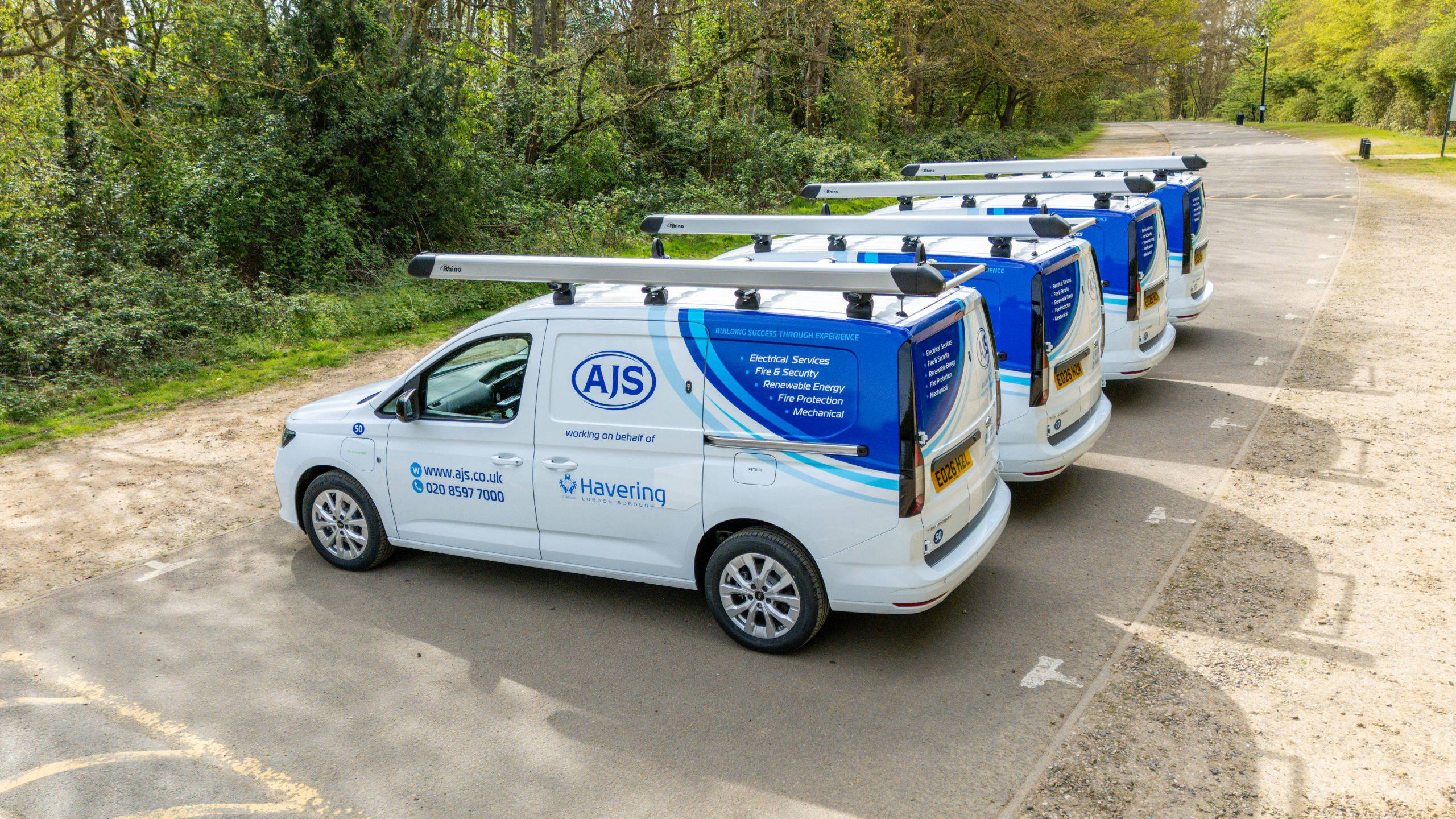 Row of new blue and white plug-in hybrid AJS vans showing Havering logo and AJS logo