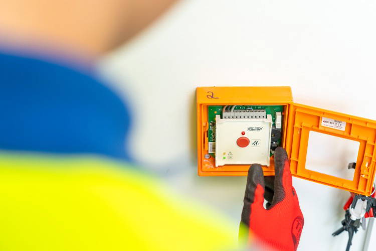 Operative doing fire safety work about to press a red button